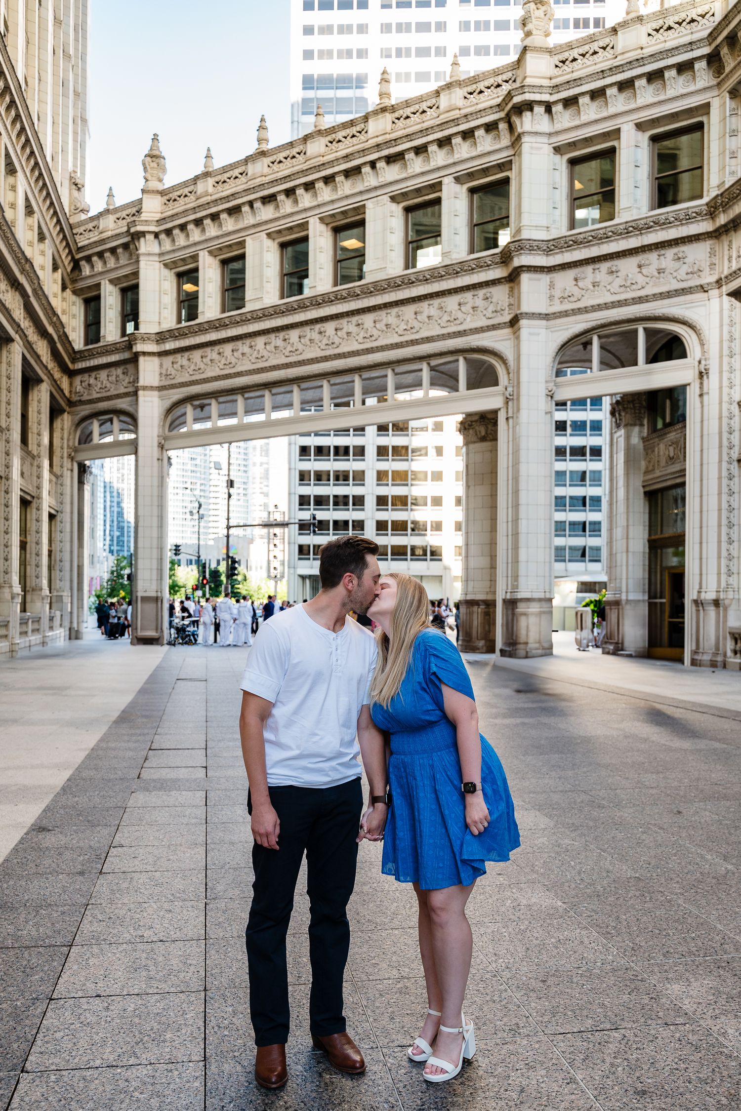 Couple sharing a romantic moment in front of a golden ornate building entrance in a city, woman in blue dress.