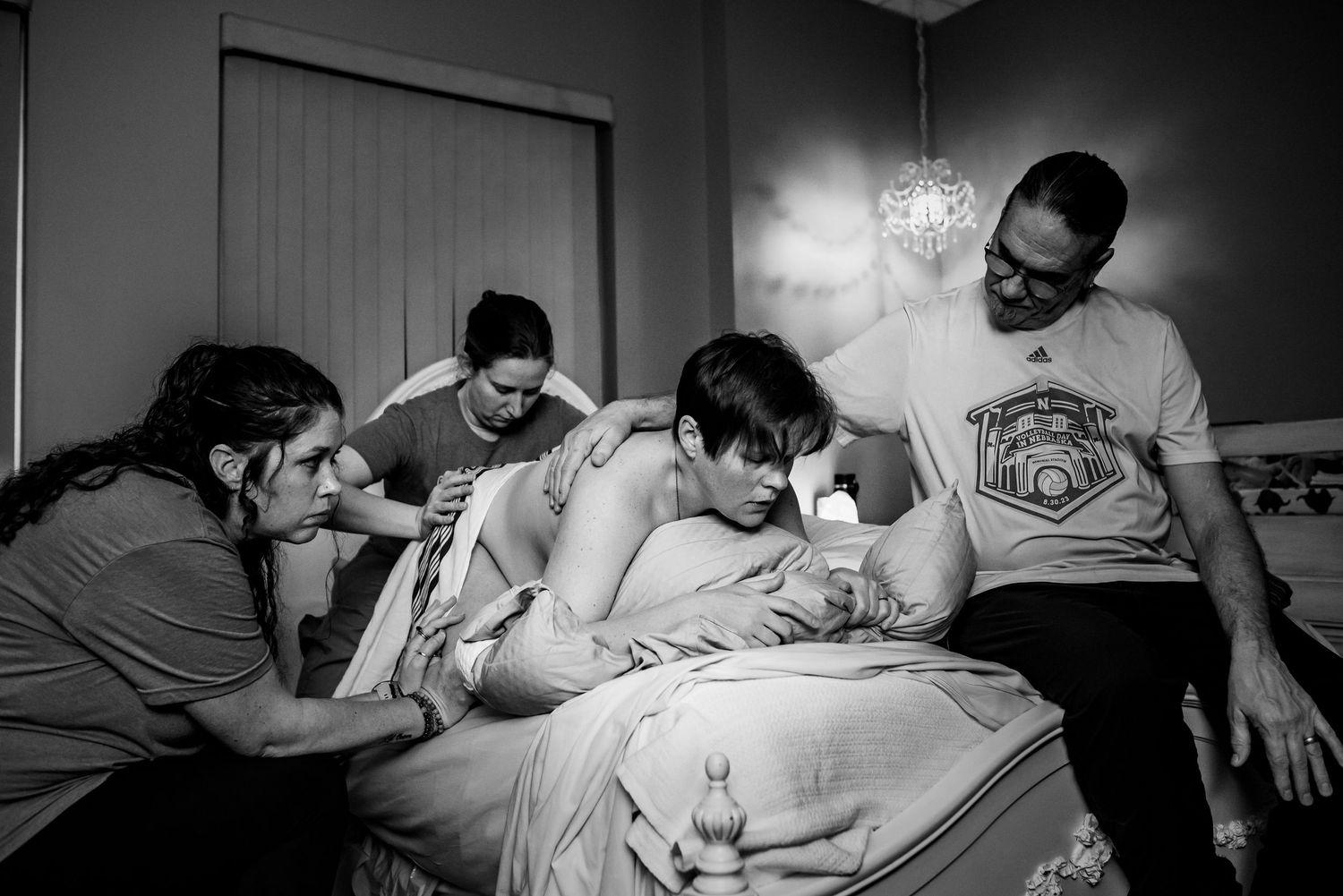 A woman in labor at the CHI Birth Center in Lincoln NE with her husband, doula, and midwife. This image is captured by Novita Birth Stories