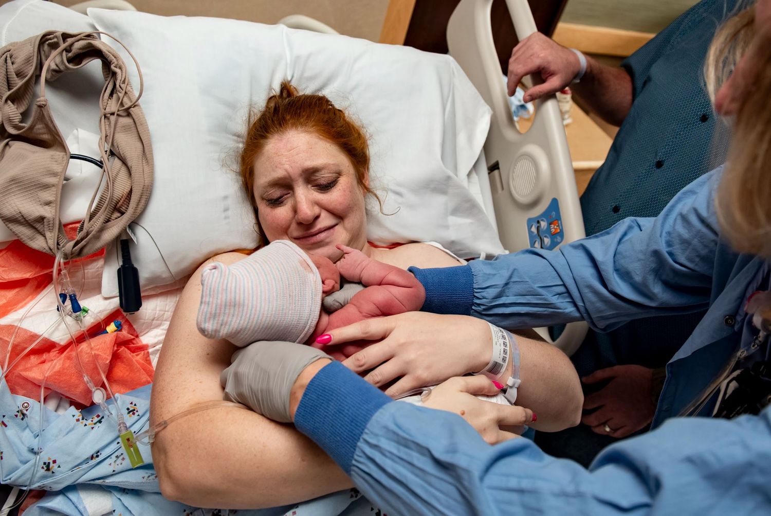 Medical staff assist with skin-to-skin contact between parent and newborn in hospital setting.