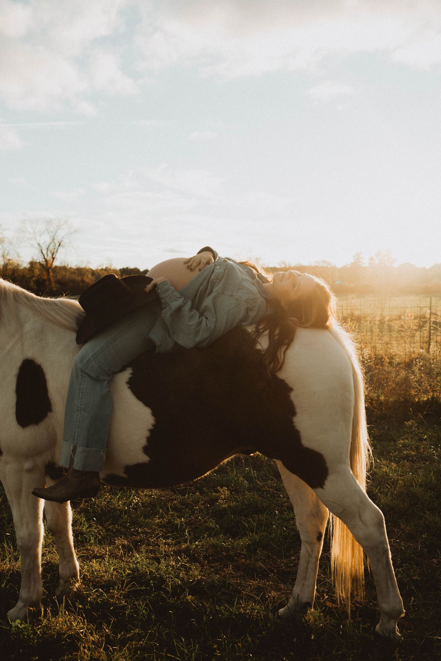 Couple in western attire sharing a moment by a Featherlite livestock trailer at golden hour sunset.