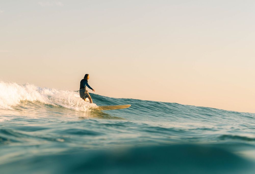 photo of a surfer about to do a turn on a blue and golden wave at sunset Bar Beach, Newcastle NSW