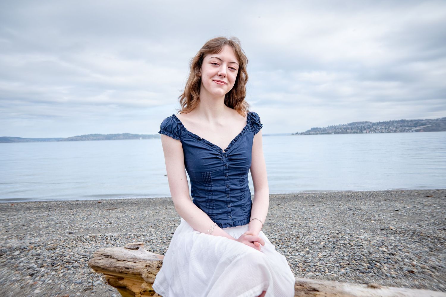 Tacoma senior photos with seated pose by the waterfront in a dress shirt and flowy skirt