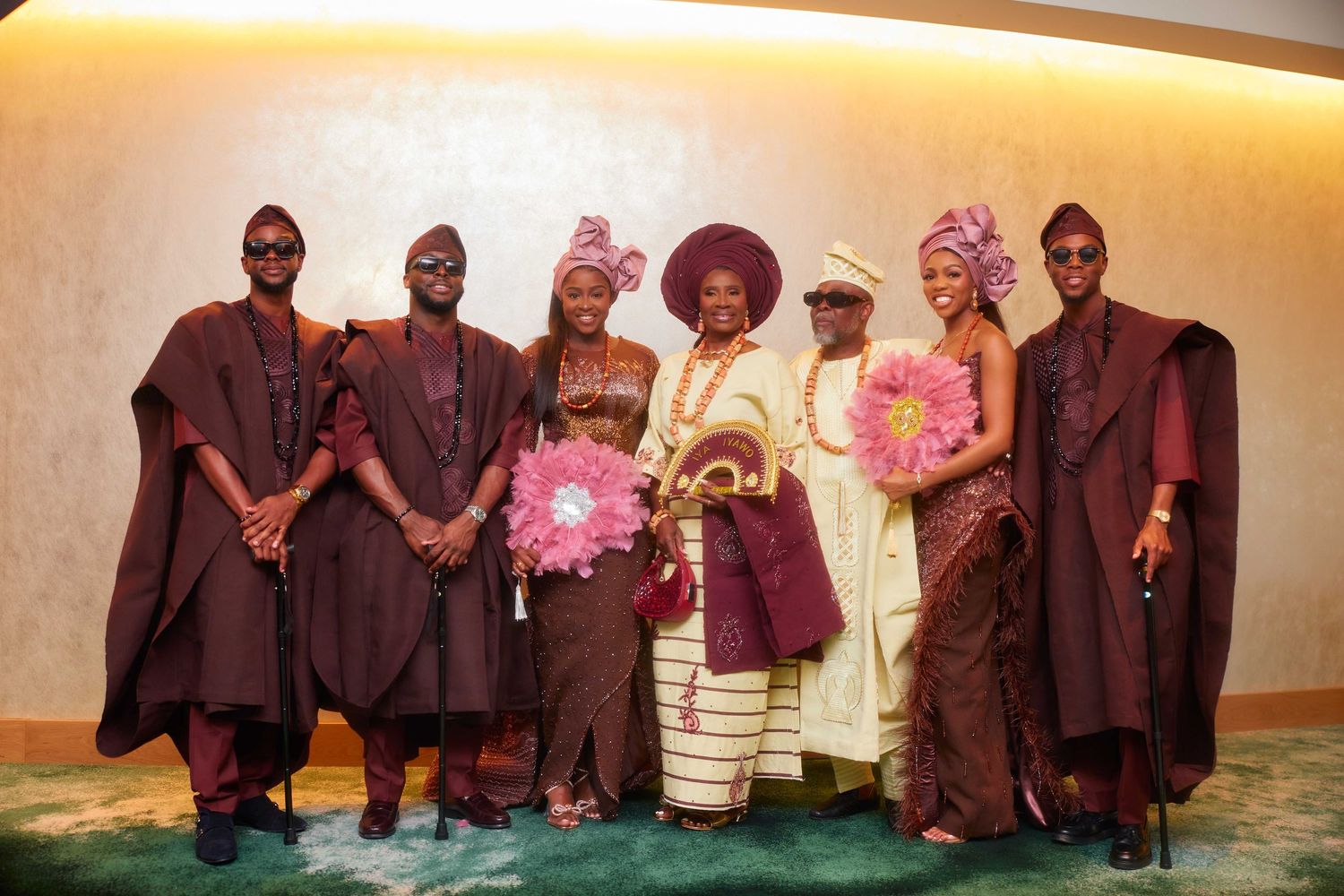 Group of seven people in traditional Nigerian attire posing together at a formal cultural celebration event.