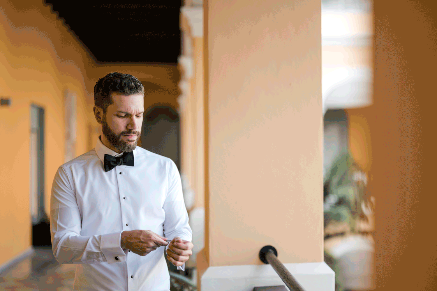 Groom adjusting his watch in a warm-toned hallway before the ceremony at Palacio Provincial