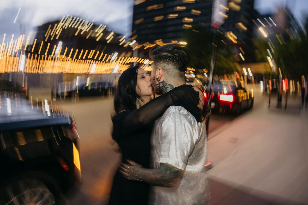 Couple sharing a romantic kiss on a Chicago street at night with bokeh lights and urban traffic in the background at Fulton Market