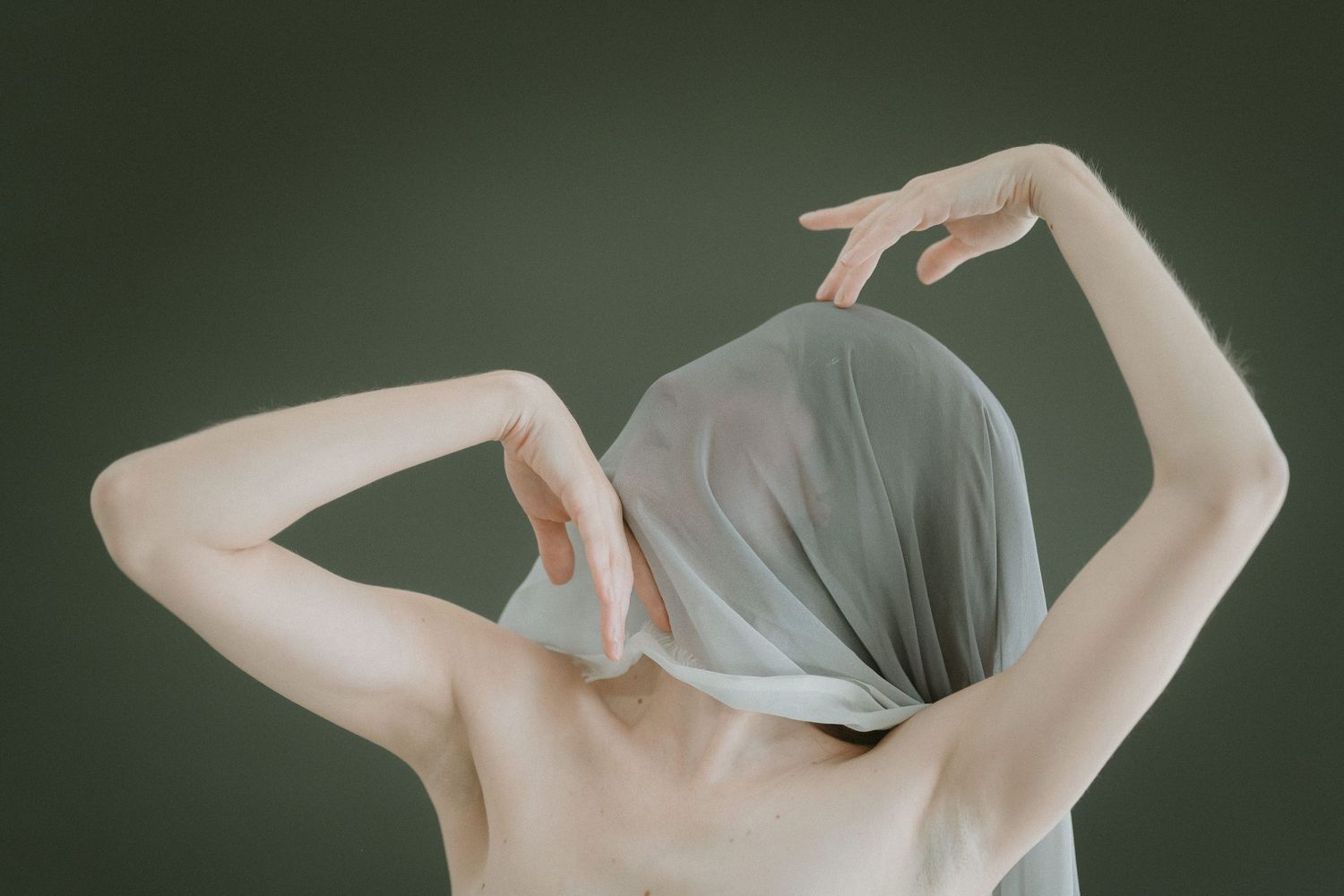 Abstract nude portrait with draped fabric creating ethereal effect.