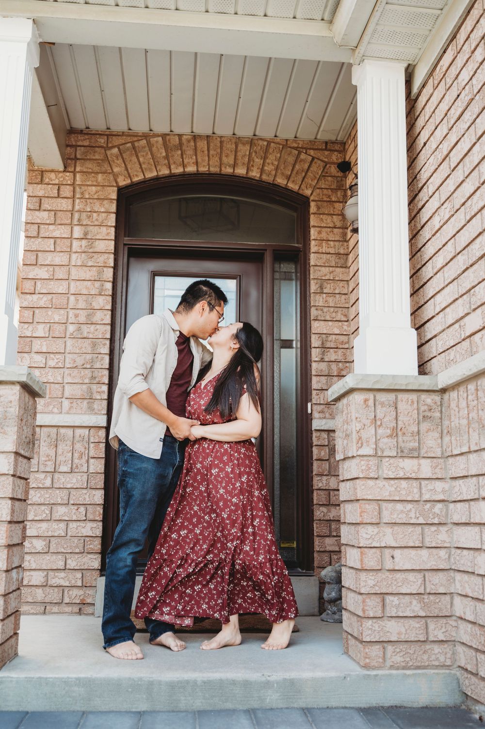 A couple stands on their front porch kissing