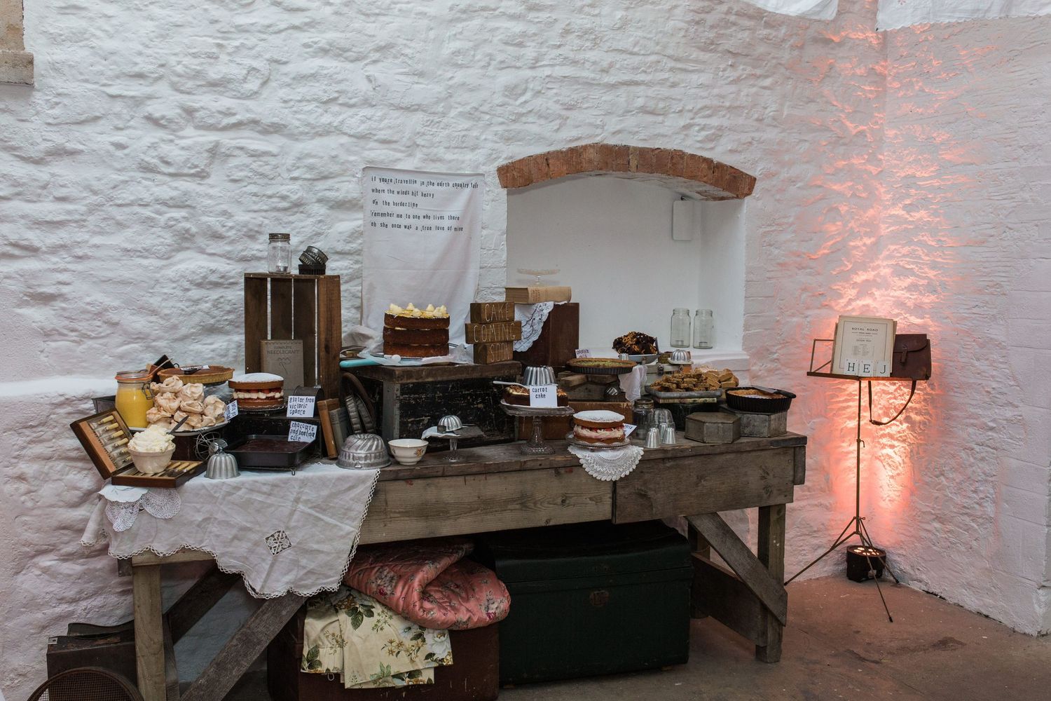 Rustic buffet table with assorted foods displayed in a whitewashed stone room with warm ambient lighting.