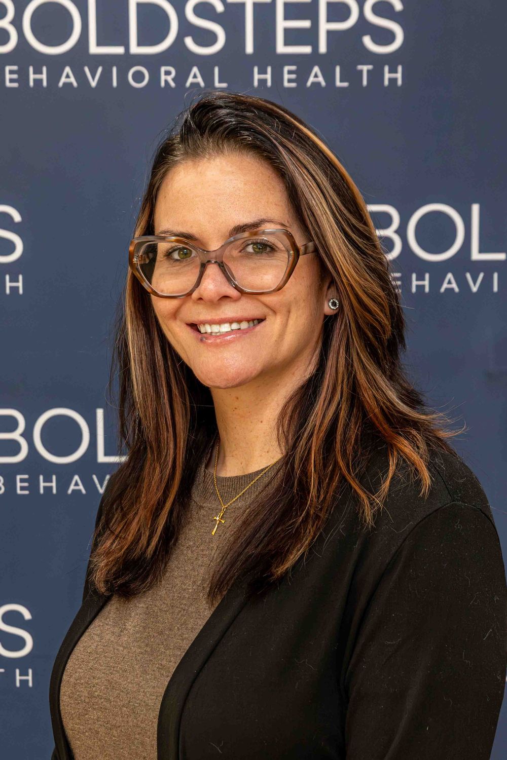 Woman with glasses and long brown hair smiling at Bold Steps Behavioral Health.