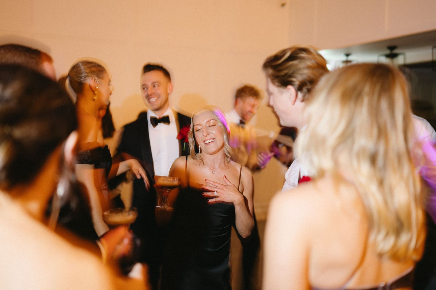 Wedding guests dancing and celebrating in formal attire at an indoor reception.