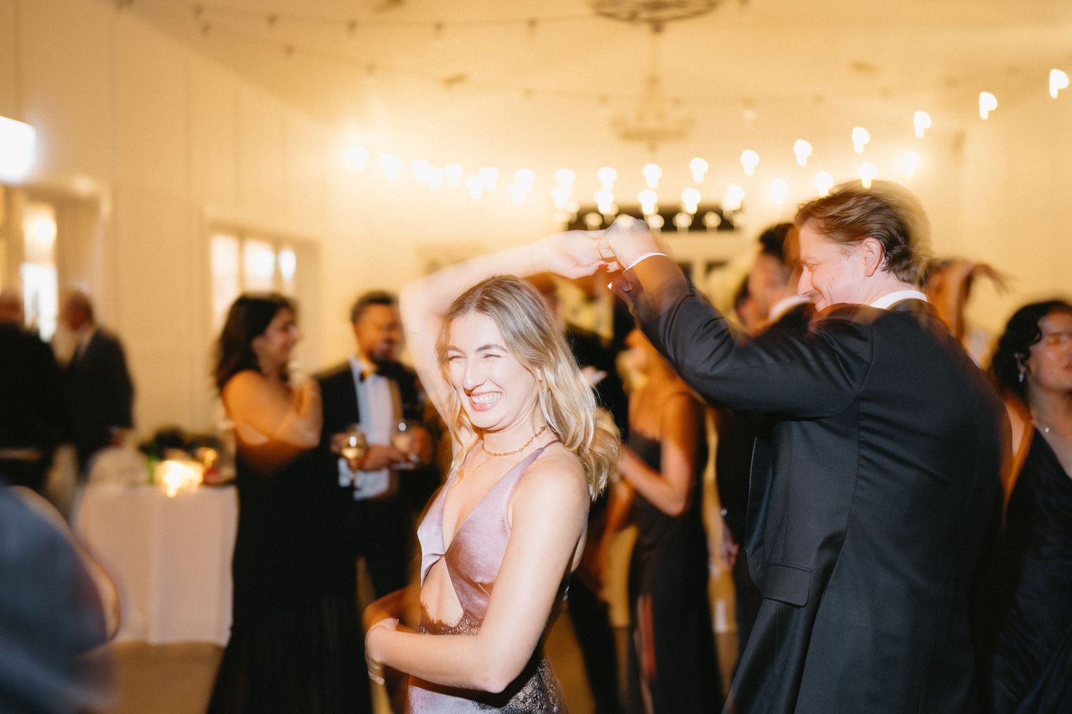 Wedding guests dancing and celebrating during a lively reception party.