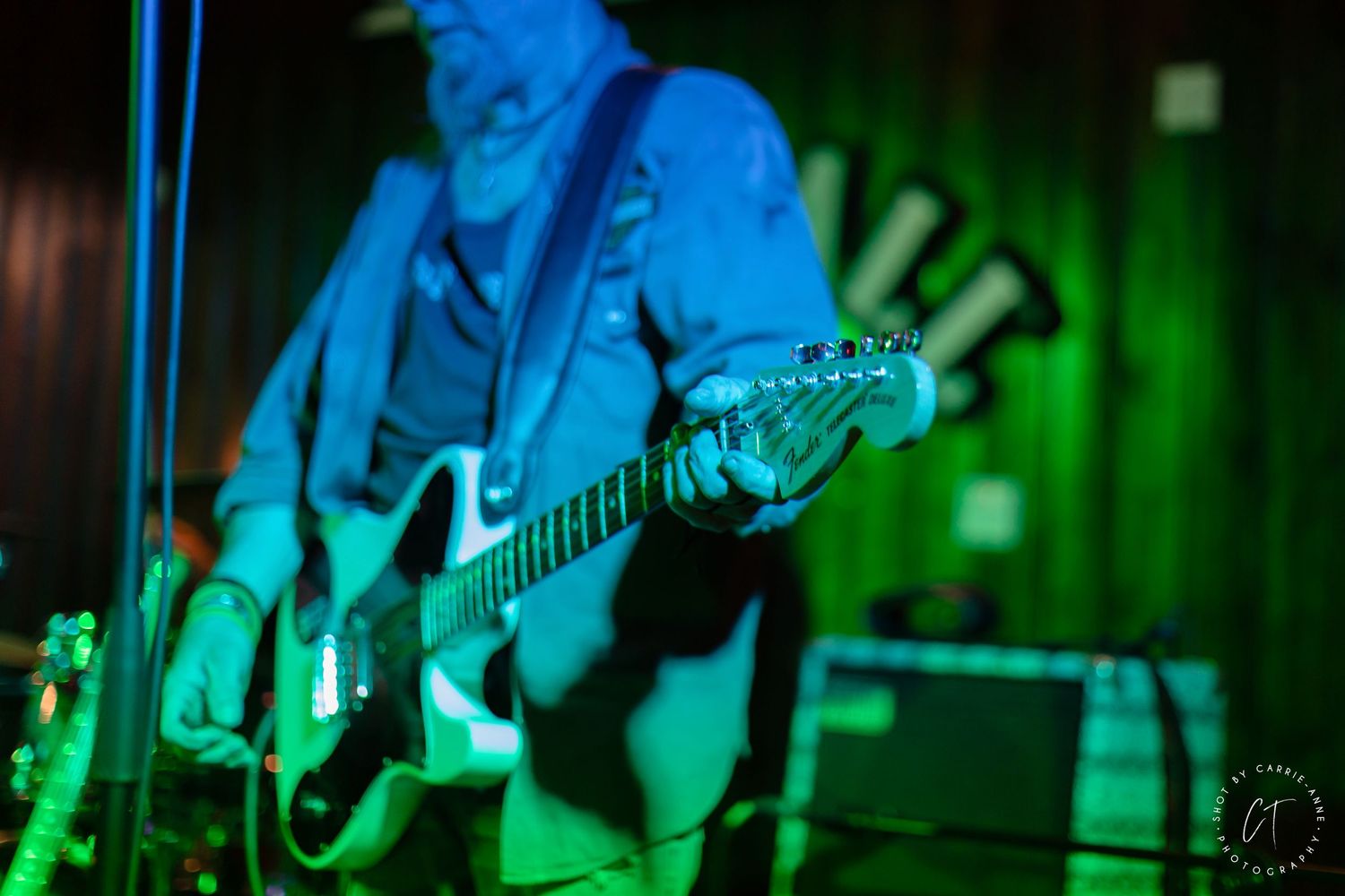 Concert performance lit with dramatic blue and green stage lighting.