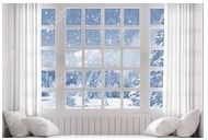 Snow covered winter scene viewed through white framed window with curtains.