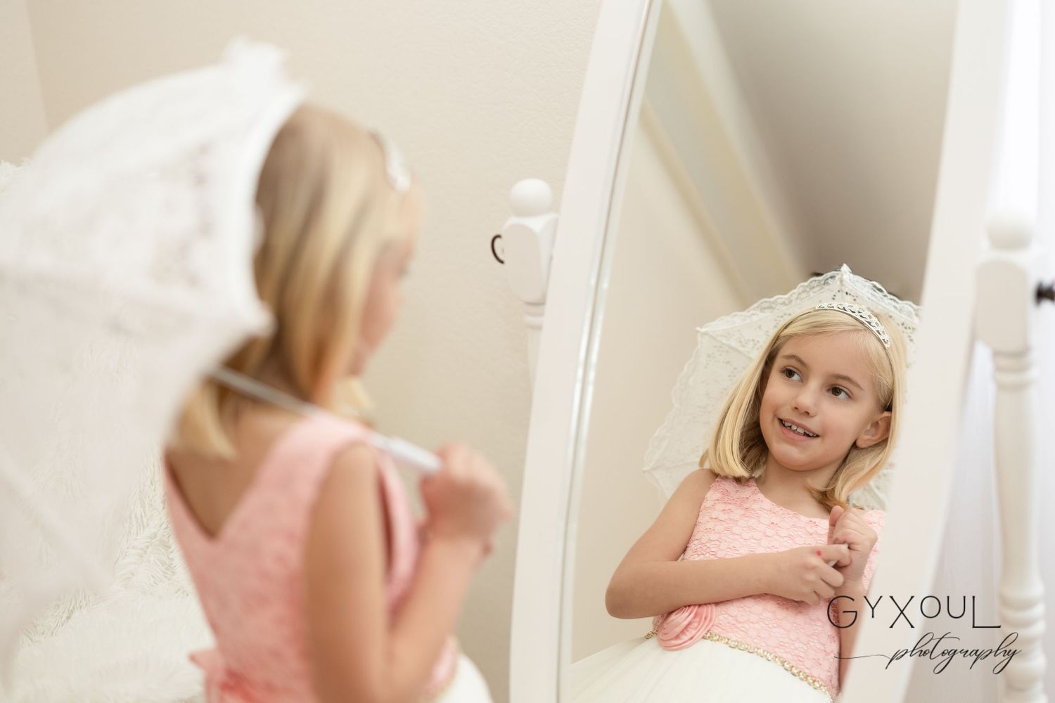 Sweet moment captured in mirror wearing pink party dress and crown.