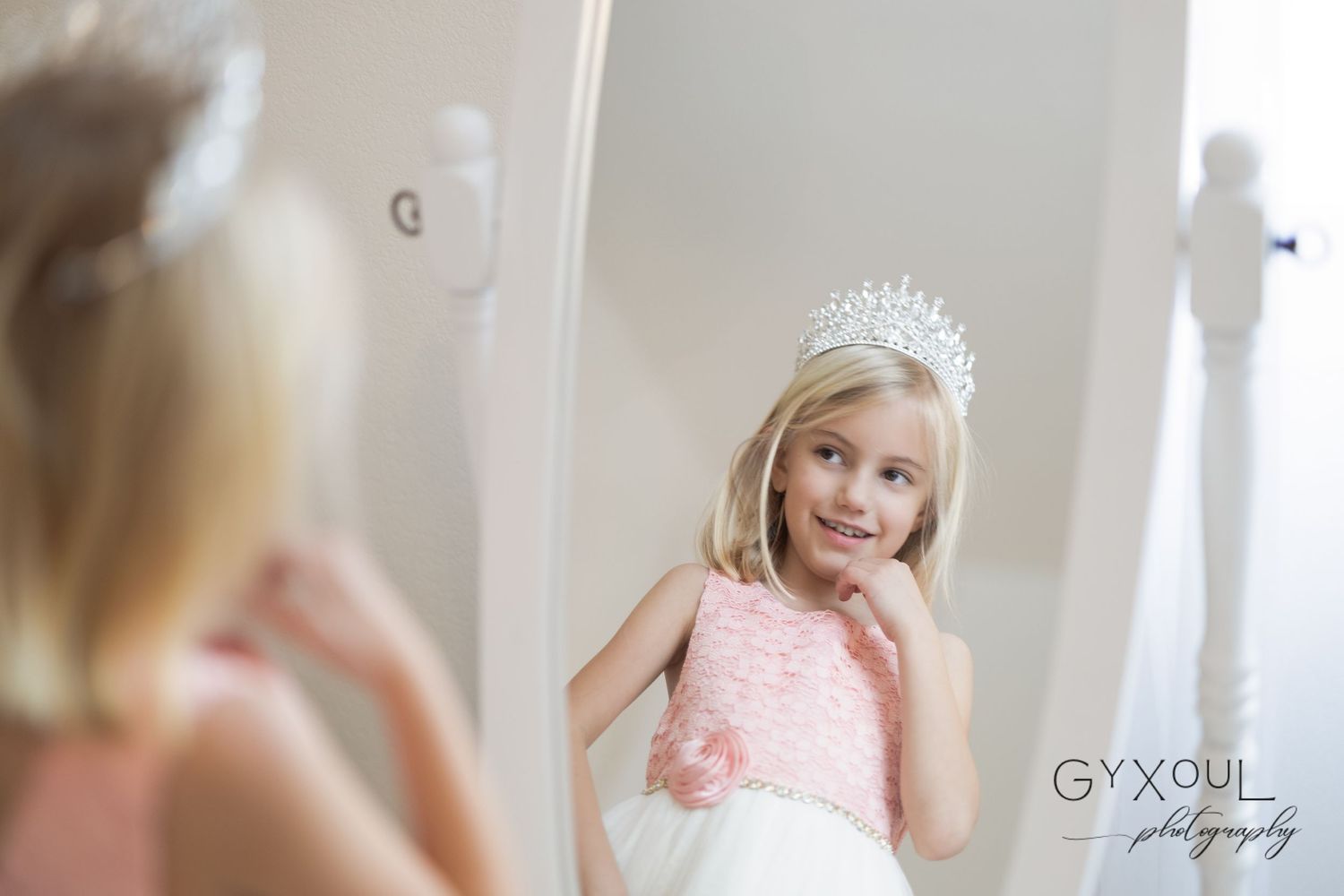 Mirror reflection shows an elegant pink and white dress with a sparkly crown.