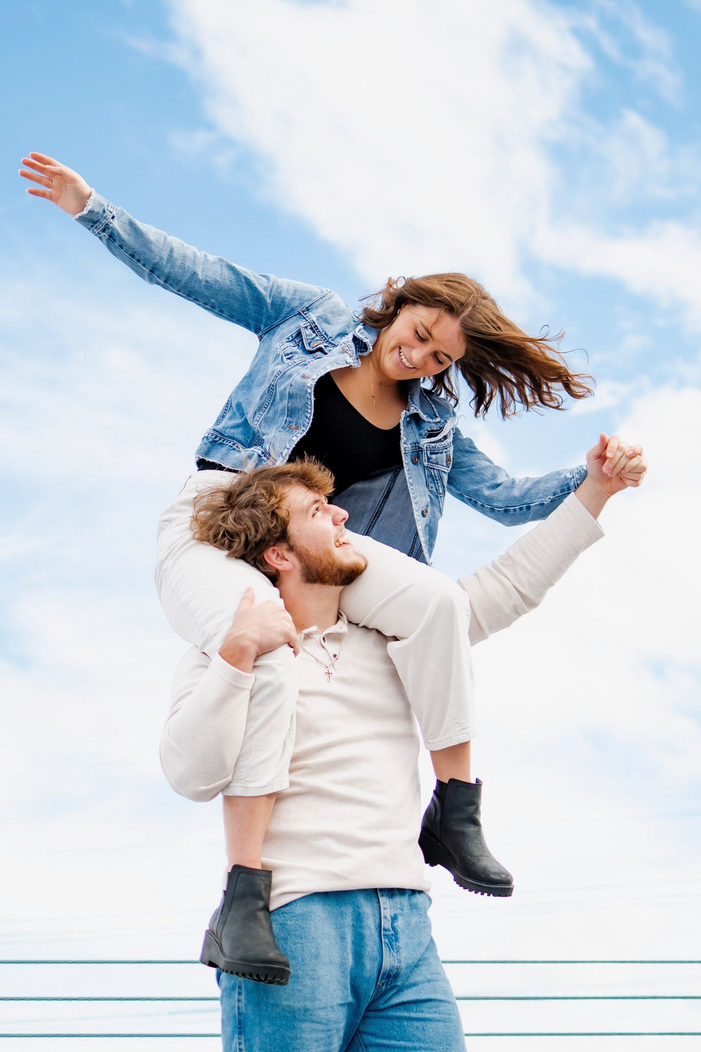 Joyful couple playing and laughing against blue sky backdrop.