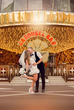 A dramatic dip kiss outside the Carousel Bar with glowing golden lights in the background.