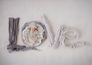 The word 'LOVE' created using artfully arranged fabric pieces in soft white and gray tones.