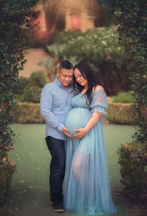 An intimate maternity photo of an expectant couple in a garden archway.