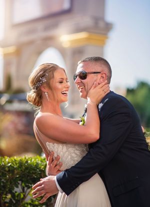 A joyful wedding moment captured outdoors with warm sunlight and architectural details.