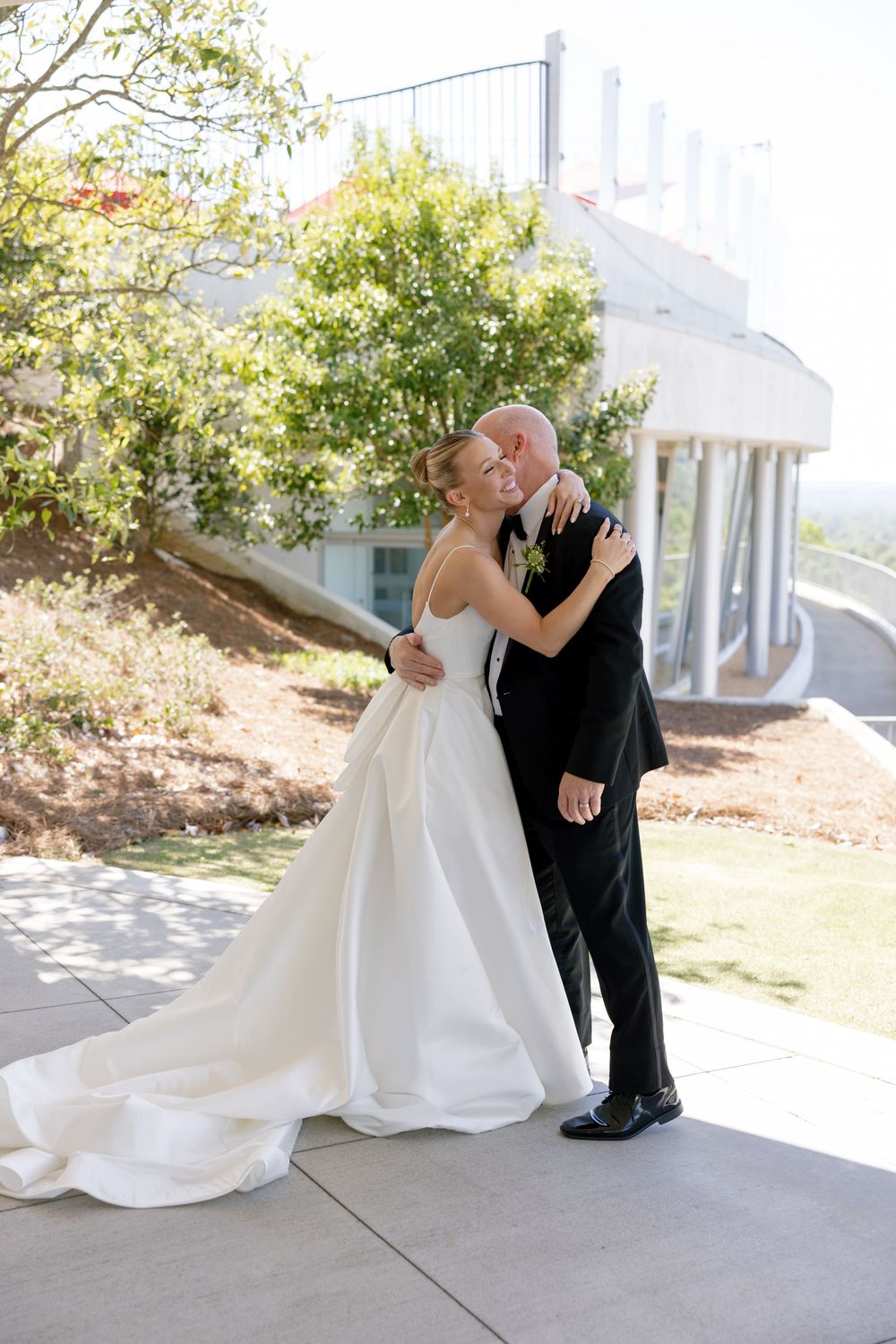 A couple shares a romantic moment on their wedding day on an outdoor patio surrounded by greenery.
