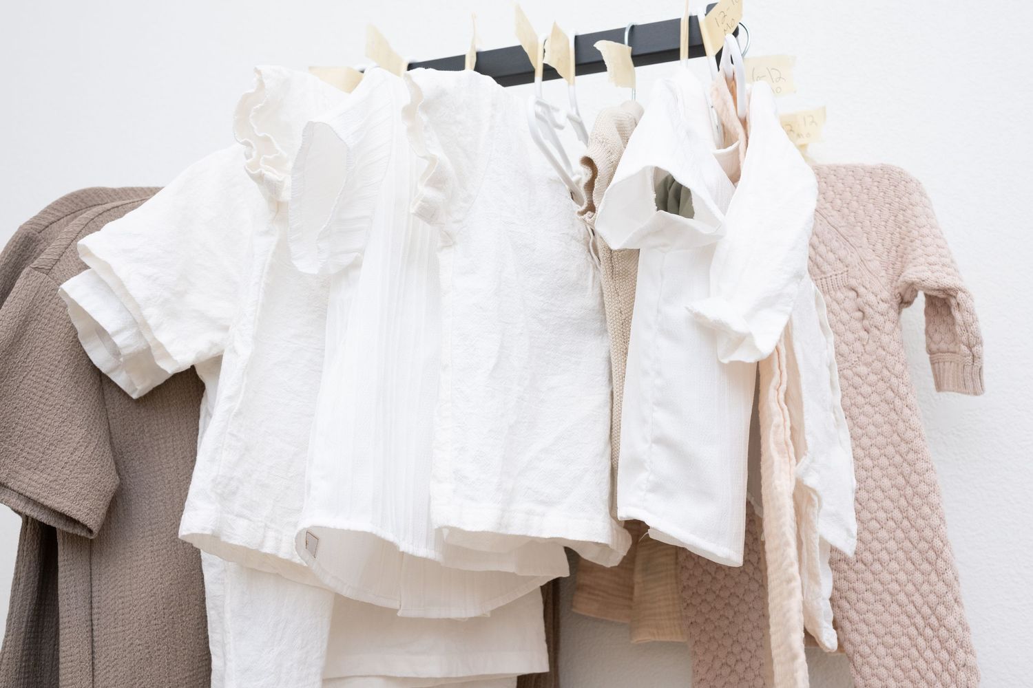 Row of delicate white clothing items hanging on display in a boutique setting.