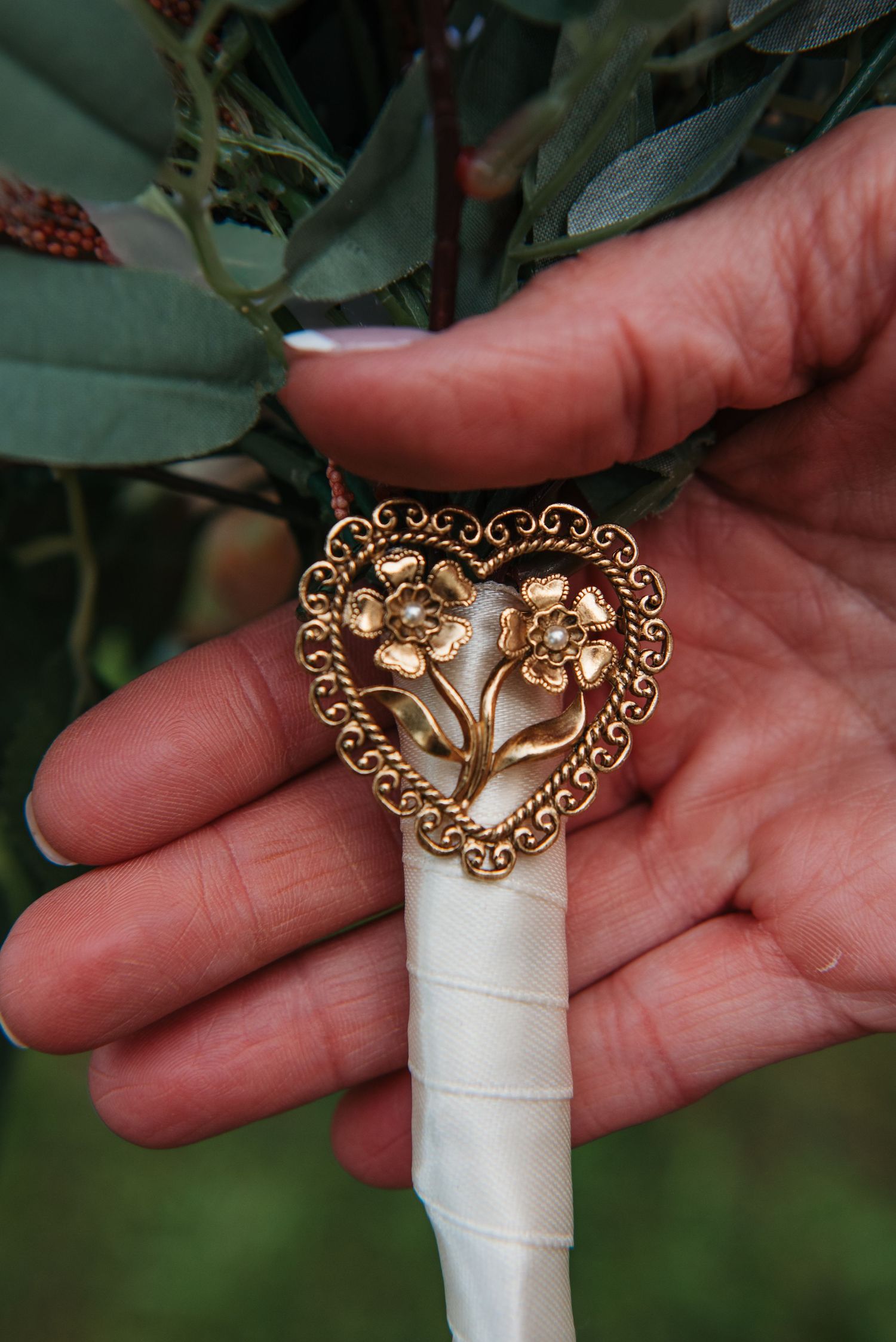 Close-up of ornate gold decorative details on a white wedding bouquet wrap.