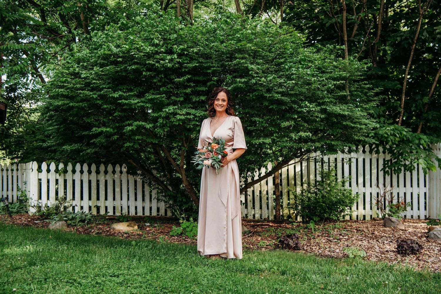 Bride in garden with white picket fence and lush greenery at the Appalachian Wedding Chapel.