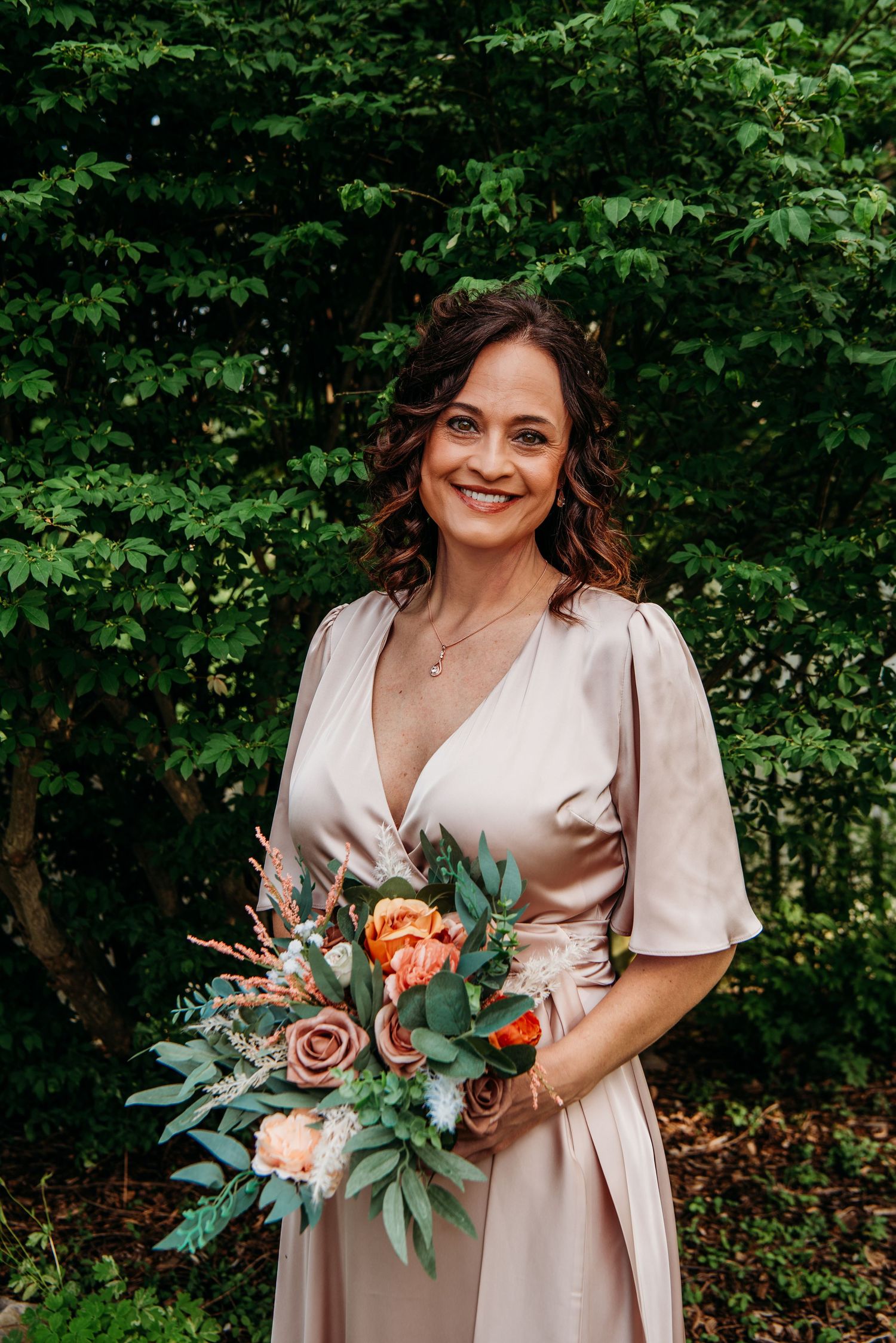 Bride in blush dress holding beautiful bouquet with peach roses and eucalyptus at the Appalachian Wedding Chapel.