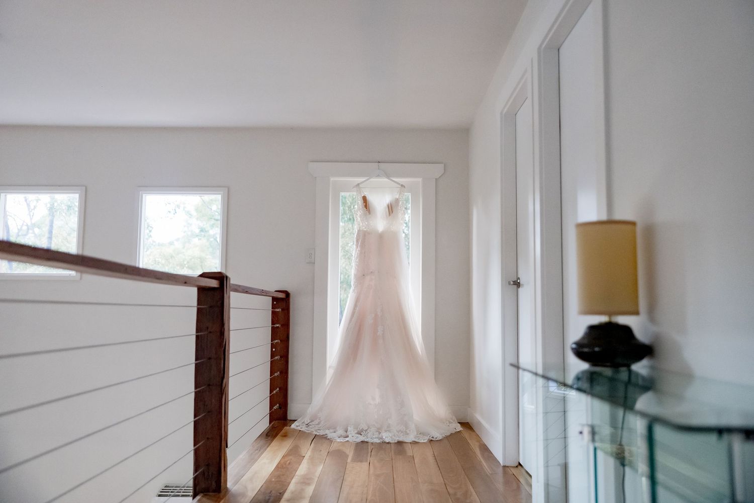 A sunlit modern interior hallway features sliding glass doors, white walls, and translucent curtains.