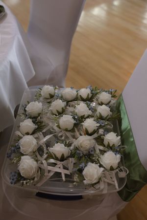 White roses and starfish arranged as wedding boutonnieres on a light surface.