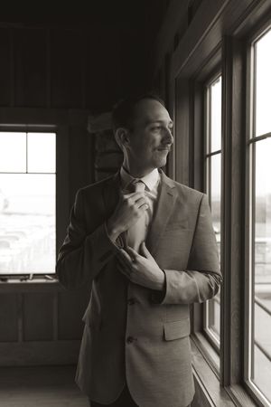 Silhouette of a person in formalwear against window light in a wooden room.