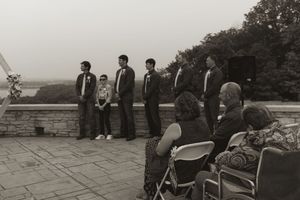 Wedding guests seated in white chairs watching an outdoor ceremony with mountain views in the background.