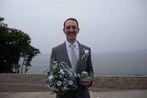 A wedding ceremony moment captured against a scenic mountain backdrop with blue and white floral decorations.