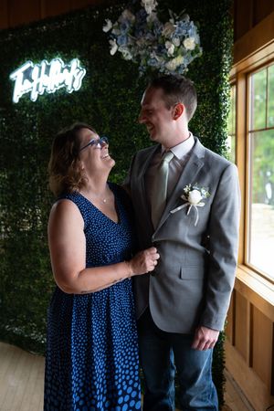 Sweet moment captured in front of a green hedge wall with neon lighting.