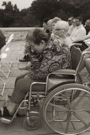 Wedding guests in wheelchairs seated in a row during an outdoor ceremony.
