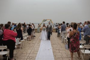 Wide view of an outdoor wedding ceremony with white chairs and stone patio overlooking a scenic vista.
