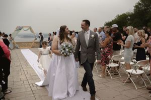 Wedding party and guests gather on a stone patio during an outdoor celebration.