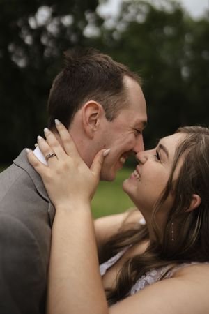 Close-up of tender wedding kiss with bride's hand on groom's face.