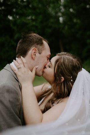 Romantic wedding portrait captures intimate moment between newlyweds outdoors.