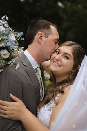 Joyful wedding couple shares romantic moment among white flowers.