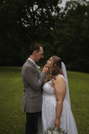 Newlyweds share intimate moment on grassy lawn during wedding.