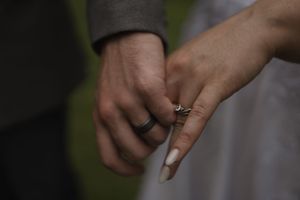 Close-up of wedding rings and hands during outdoor ceremony.