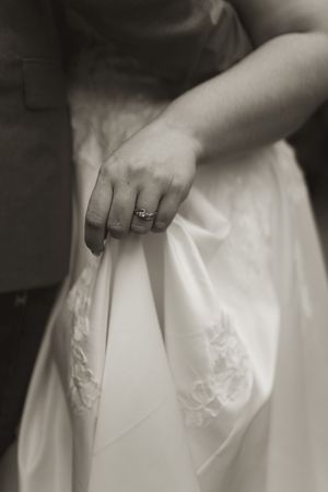 Detail shot of hands holding white lace wedding dress fabric.