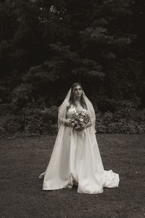 Artistic black and white portraits of a bride in her wedding dress against a dark natural backdrop.