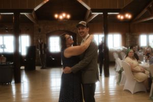 A wedding reception dance taking place in a rustic wooden barn with ambient lighting.