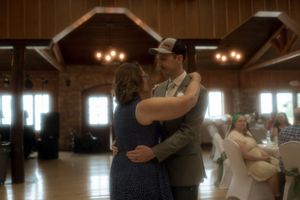 Couples dancing together during a wedding reception in a warmly lit wooden venue.