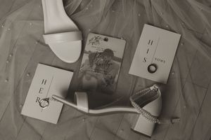 Wedding detail shots of rings and decorative elements arranged on white paper.