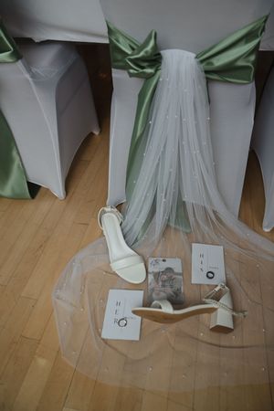 Wedding dress details with mint green accents and paper elements on a wooden floor.