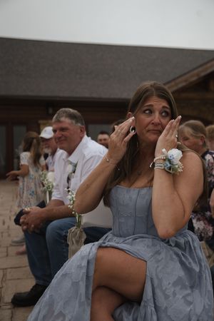 Bridesmaids in periwinkle dresses share emotional moments during outdoor wedding ceremony.